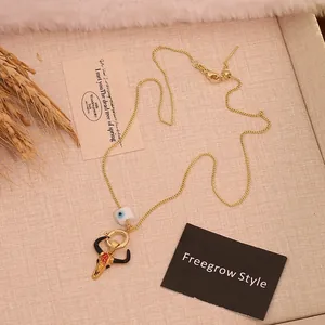 Detail of vintage bull head pendant with evil eye bead on a golden sweater chain