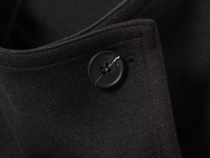 Detail of a black coat collar with a textured button and fine fabric weave