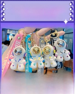 Close-up of four colorful astronaut keychains with metallic visors and SPACE hand straps