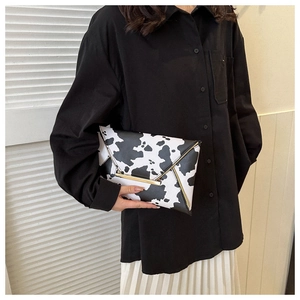 Detail of a cow print envelope clutch featuring a gold metal bar and stylish buckle