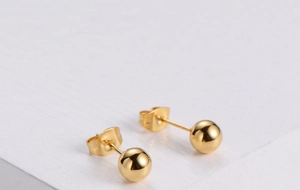 Close-up of polished gold ball stud earrings featuring a high-gloss mirror finish
