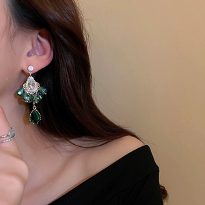 Close-up of bohemian water drop earrings with green crystals worn by a model