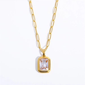 Detailed macro of emerald-cut clear crystal pendant with gold paperclip chain