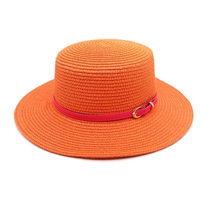 Detail of orange straw hat featuring a fuchsia leather band and gold buckle accent