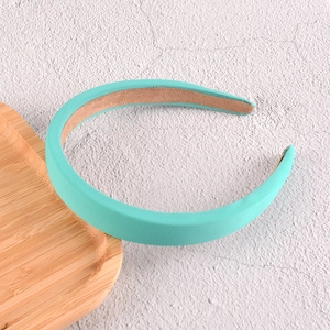 Détail d'un serre-tête rembourré vert menthe en tissu texturé sur plateau en bois