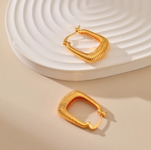 U-shaped gold plated chunky earrings with elegant spiral spring texture on beige stone