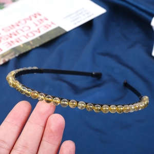 Detailed macro view of 6mm golden rutile quartz beads on a thin black wire headband