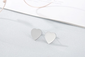 Detailed macro shot of silver heart stud earrings with a polished metallic finish