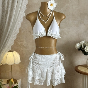 Close-up of white ruffled bikini top and floral lace skirt with drawstring detail