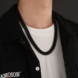 Close-up of a polished black stainless steel Cuban link chain necklace worn by a male model