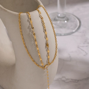 Double-layer gold zircon chain necklace on white ceramic vase with marble background