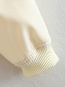 Detailed macro shot of the cream-colored ribbed elastic cuffs on the women's woven jacket