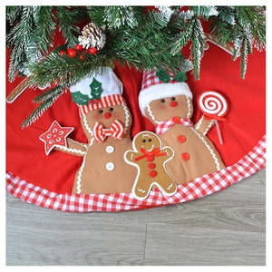 Detail of red Christmas tree skirt featuring gingerbread men and wood floor background