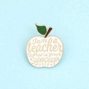 Detail of apple-shaped enamel brooch with I am a teacher what is your superpower text