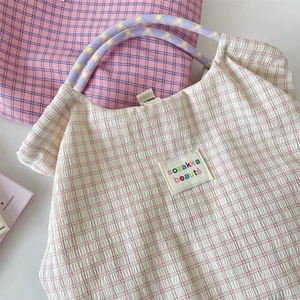 Dettaglio macro del tessuto seersucker a quadretti e toppa con logo sulla borsa tote