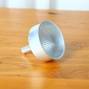 Macro detail of Italian aluminum moka pot funnel with micro-hole filter on wooden surface