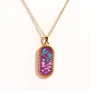 Detailed macro of 14k gold-plated tarot pendant with purple enamel and floral design