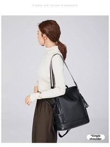 Close-up of black pebbled leather backpack worn as a stylish shoulder bag with long tassel