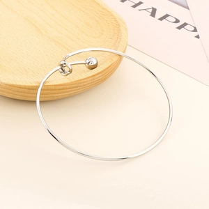 Detailed close-up of a silver minimalist bead bangle on a wooden tray surface
