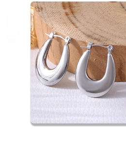 Close-up of silver U-shaped textured earrings on white leather with wooden decor