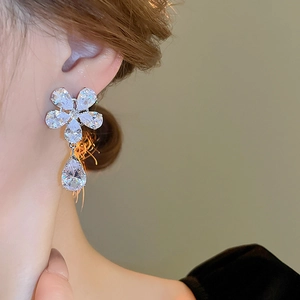 Detail of silver flower earrings with zircon inlays and large teardrop gemstone drop