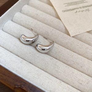 Detailed view of polished silver teardrop earrings on a velvet jewelry display tray