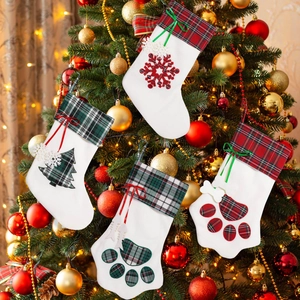 Close-up of festive plaid Christmas stockings with dog paw shapes hanging on a holiday tree