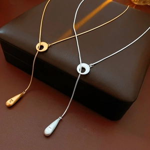 Close-up of gold and silver teardrop pendant necklaces on brown leather background