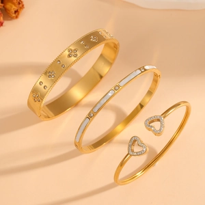 Detailed set of three 18k gold plated stainless steel bangles with floral and heart patterns