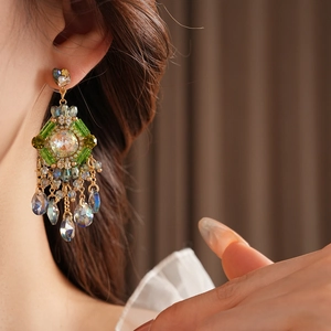 Detail of bohemian drop earrings with green crystals and iridescent tassels on model