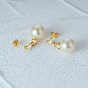 Detail of s925 silver pearl earrings with marquise zircon in golden finish