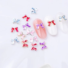 Detailed view of colorful 3D alloy bow nail charms with rhinestones on white background