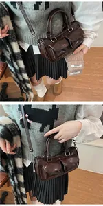 Detail of dark brown patent leather saddle bag with double front pockets and strap