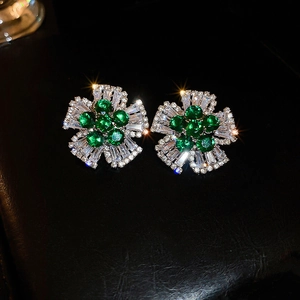Détail macro de boucles d'oreilles fleur en argent avec cœur vert et cristaux brillants