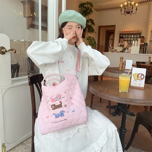 Detailed close-up of pink quilted tote bag featuring cute cartoon cat embroidery and soft texture
