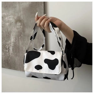 Close-up of cow print handbag featuring black and white spots and a durable carry handle