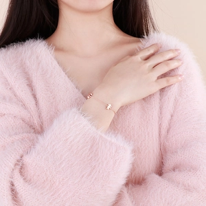 Elegant rose gold stainless steel bracelet with cute girl charms on a pink sweater