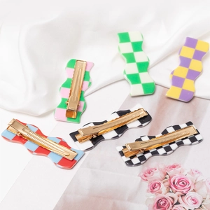 Set of wavy checkerboard hair clips in vibrant colors on a white silk background