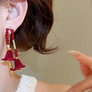 Primo piano di orecchini vintage con fiori di velluto rosso e perle sul modello