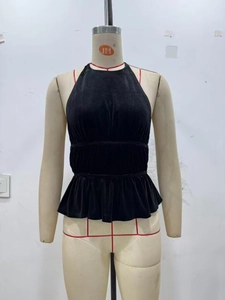 Dettaglio del top allacciato al collo in velluto nero con vita smock e orlo a peplo