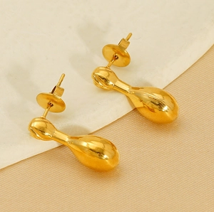 Macro view of golden teardrop stud earrings with a polished finish on textured stone