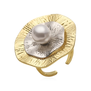 Detailed macro of gold and silver textured metal petals with a white pearl on a ring