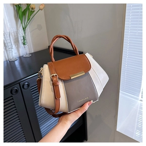 Close-up of tricolor leather handbag with gold hardware and woven handle detail