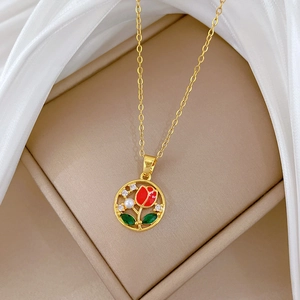 Macro detail of gold necklace pendant with red tulip, pearl and crystal inlay