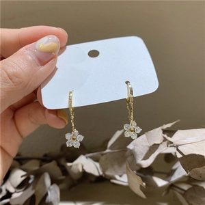 Detailed view of dangling gold flower earrings with sparkling cubic zirconia petals