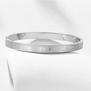 Detailed macro view of silver titanium steel bangle with etched LOVE geometric pattern