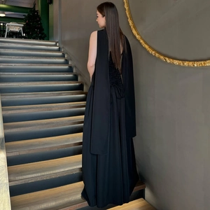 Elegant back view of long black backless dress with lace-up ribbon details on stairs