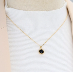 Detail of 18K gold-plated necklace featuring a round black agate pendant on neck model