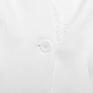 Close-up of a white four-hole button and delicate lace trim on a professional blazer