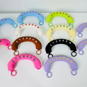 Detailed close-up of colorful crescent fabric charms with STANNUM embroidery and plastic rings